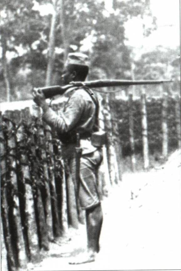 Soldado nativo de guarda à paliçada de um forte na fronteira do Rovuma, Moçambique